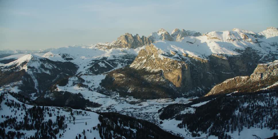 Large mountains partially covered in snow and trees on sunny day