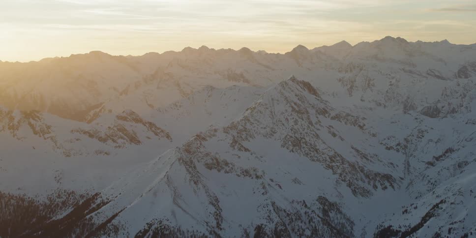 Sunlight is streaming onto a mountain range covered in snow