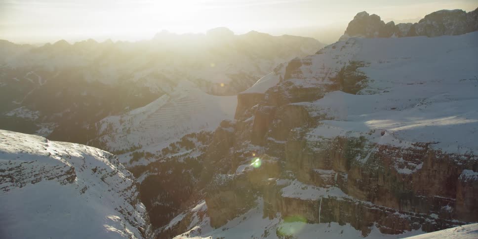 The sun sets over snowy mountains