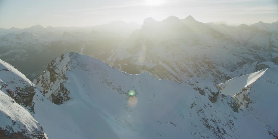The sun is shining high above the mountains