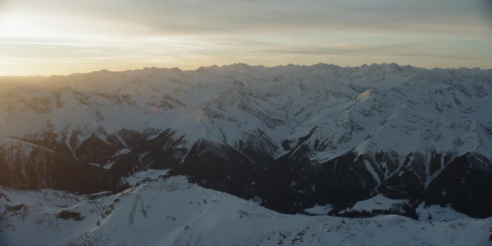 The sun sets over snowy mountains