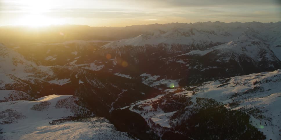 The sun sets over snowy mountains