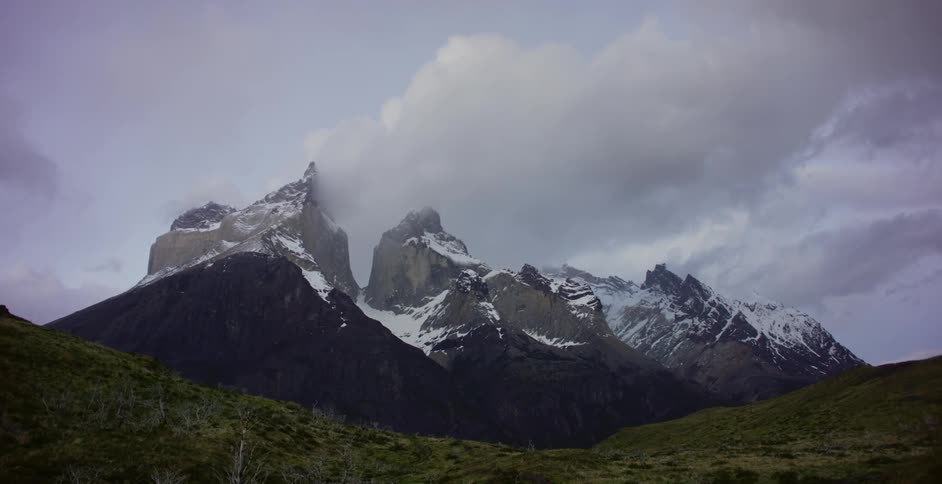 Clouds pass above a snow covered mountain top