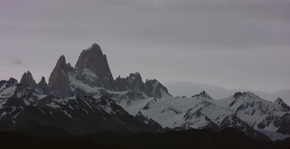The tall mountains reach into the cloudy sky