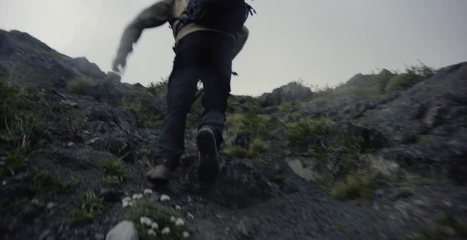 The man is climbing up the mountain carrying a camera