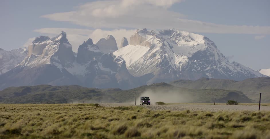 An suv is speeding along a dirt road in a remote landscape during daylight