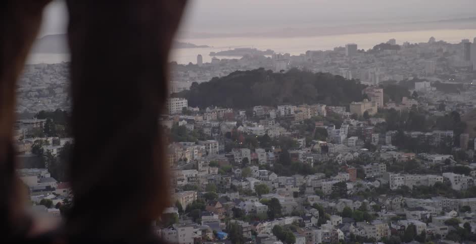 Person standing up high over a large town on a cloudy day