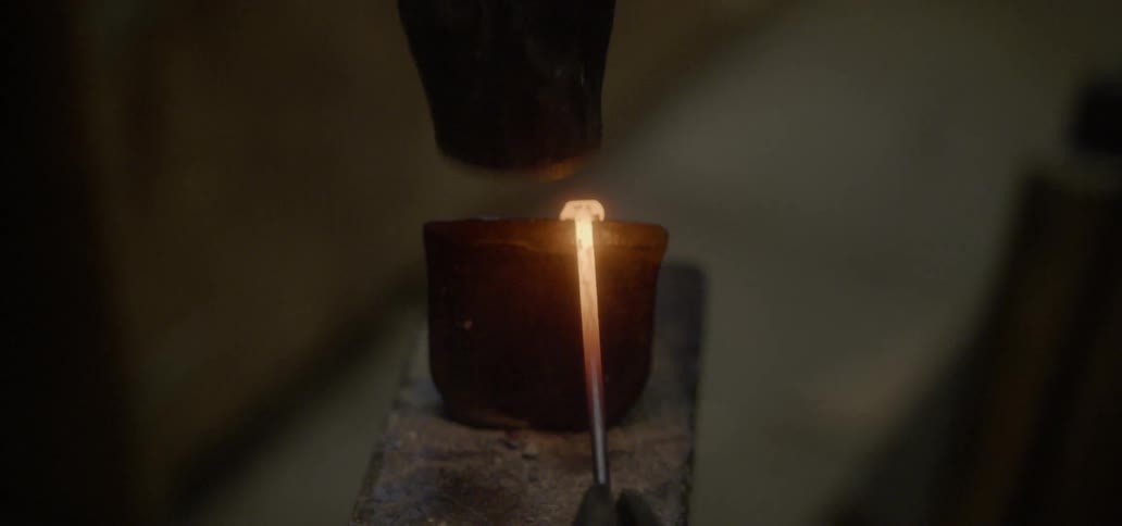 A blacksmith hammers a hot piece of metal