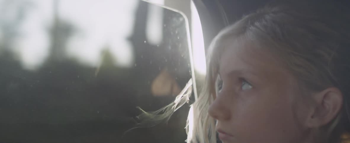 A girl looks out the window of a moving car