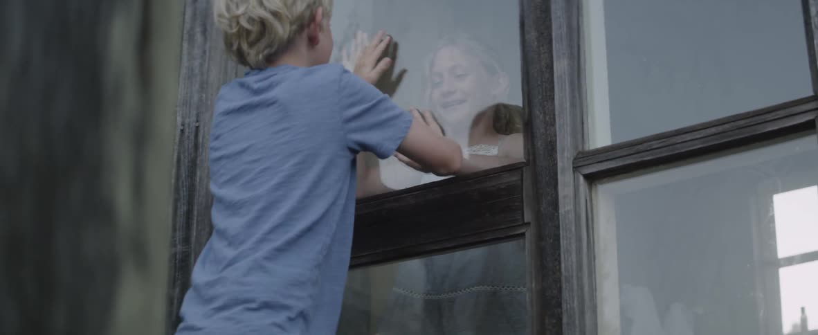 Two children play next to a window