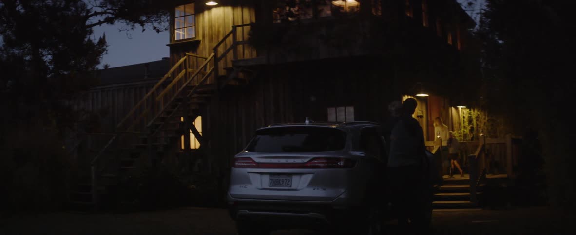 A family exit the car to enter the house at dawn