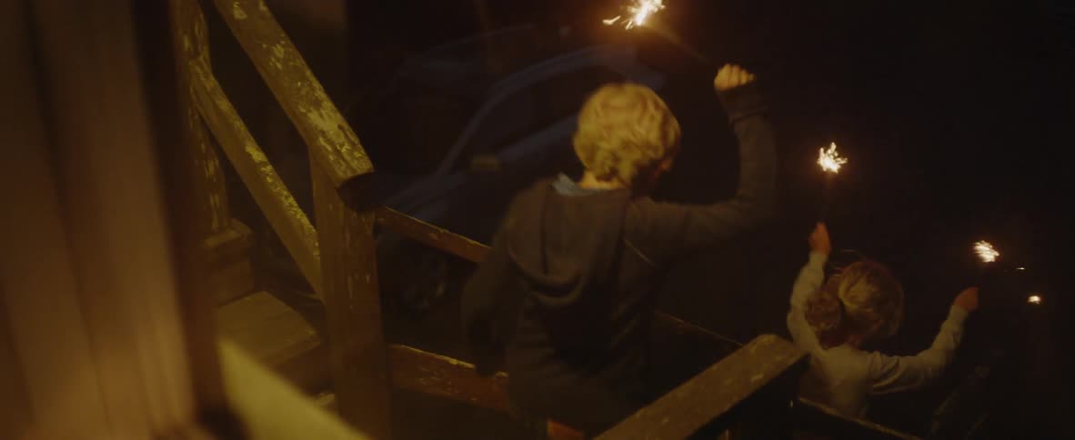 Two children run and play while holding sparklers