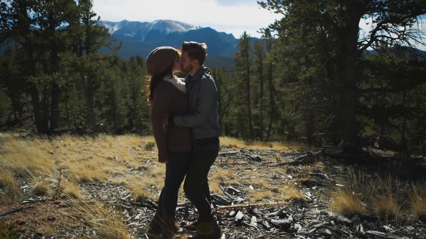 Man and woman are kissing in the woods
