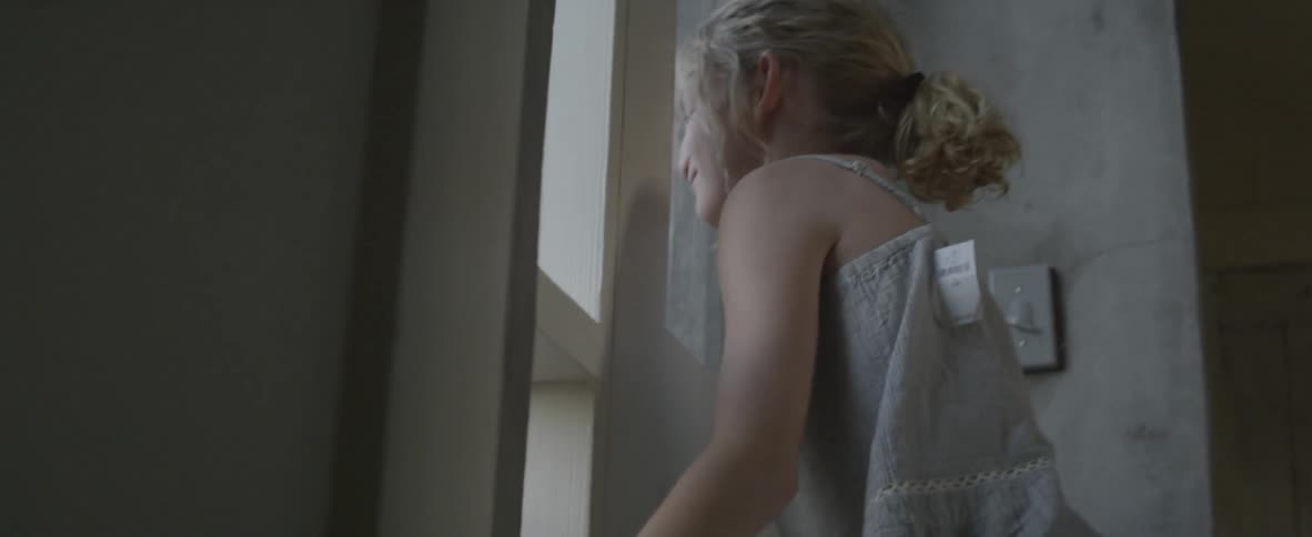 A girl laughing while playing through a window