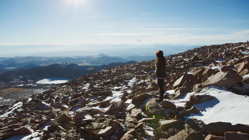A woman is hiking across boulders