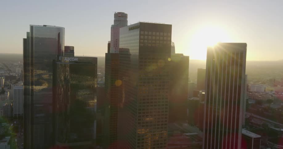 The sun is setting in the distance behind these tall buildings