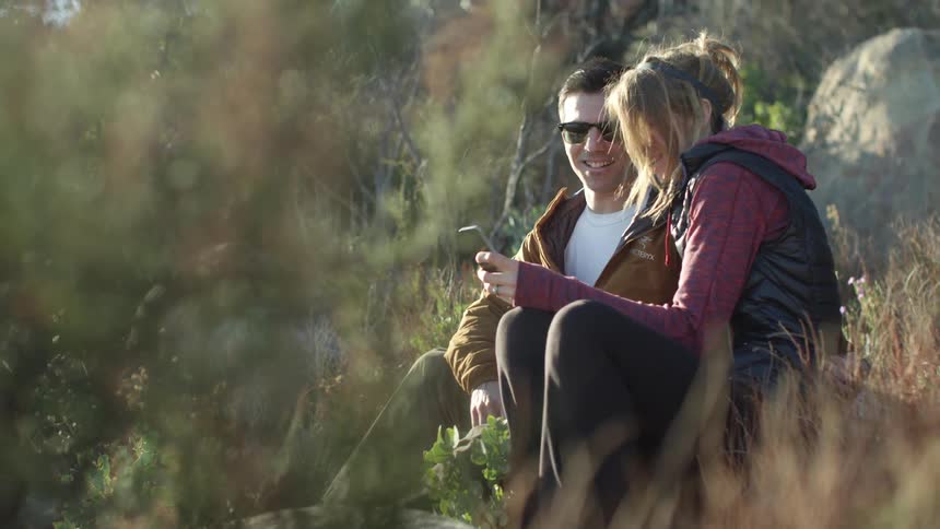 Man and woman are looking at a cellphone in the wilderness