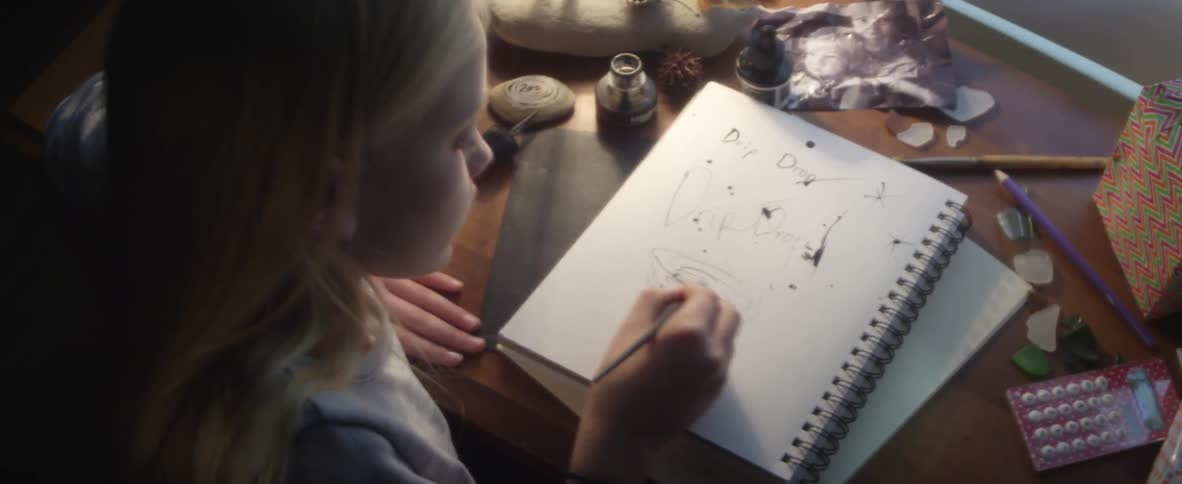 A blonde girl drawing in a notebook