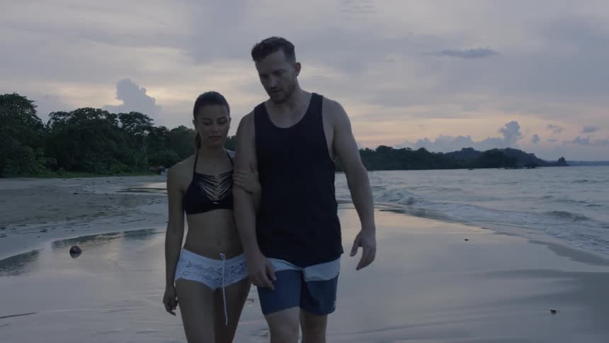 A couple walk hand in hand on the beach