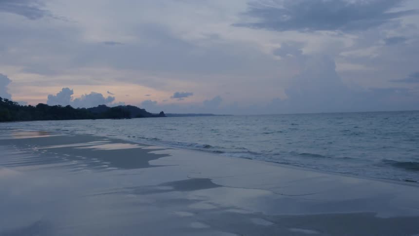 The waves slowly hit the shore at sunset