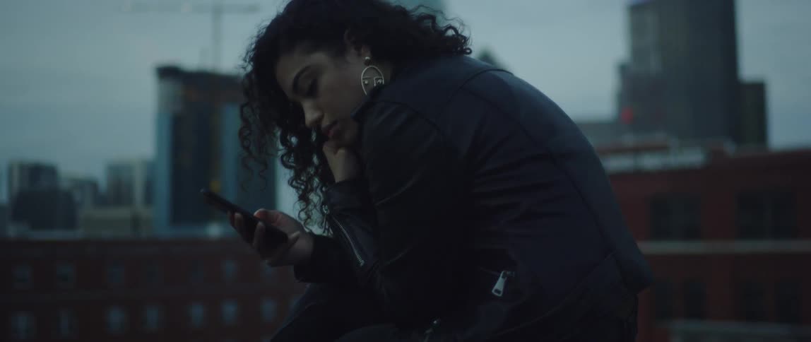 A woman uses her phone on a rooftop