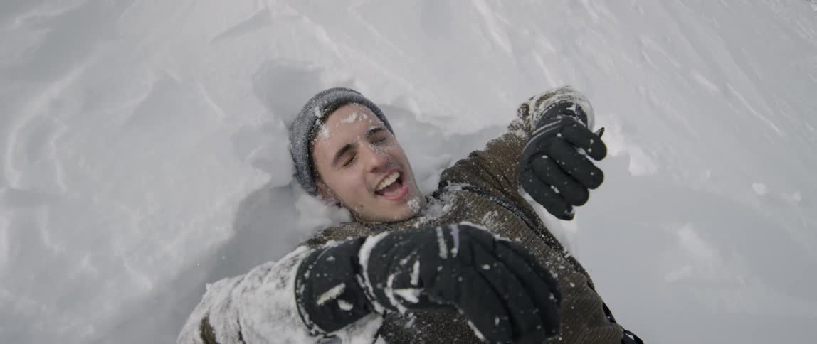 Man lays back in the snow smiling