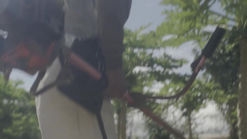 A person starts a trimmer and picks it up