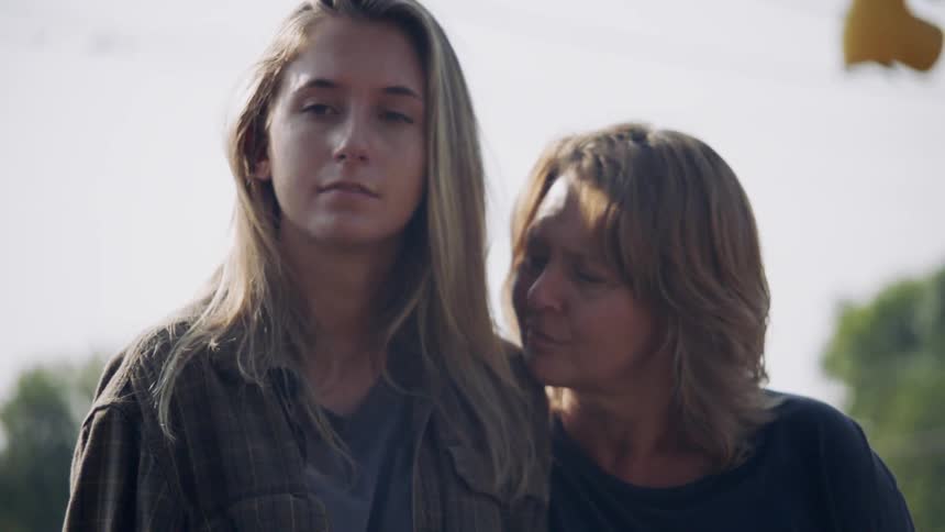 Two women standing outside with sun shining down on them