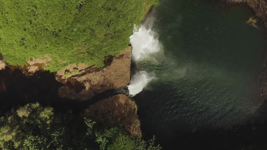 A waterfall is falling down as viewed from a drone high above