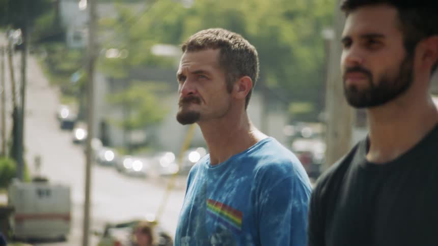 Two men stand outside on the street together