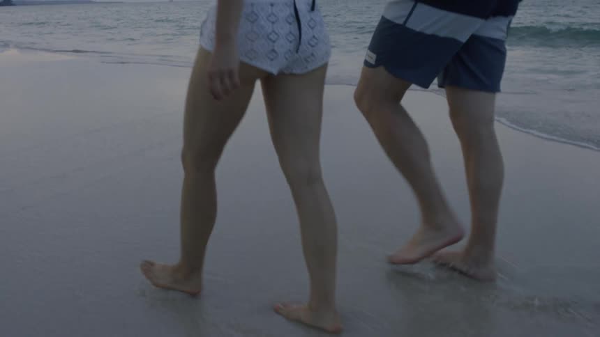 A couple walk hand in hand on the beach