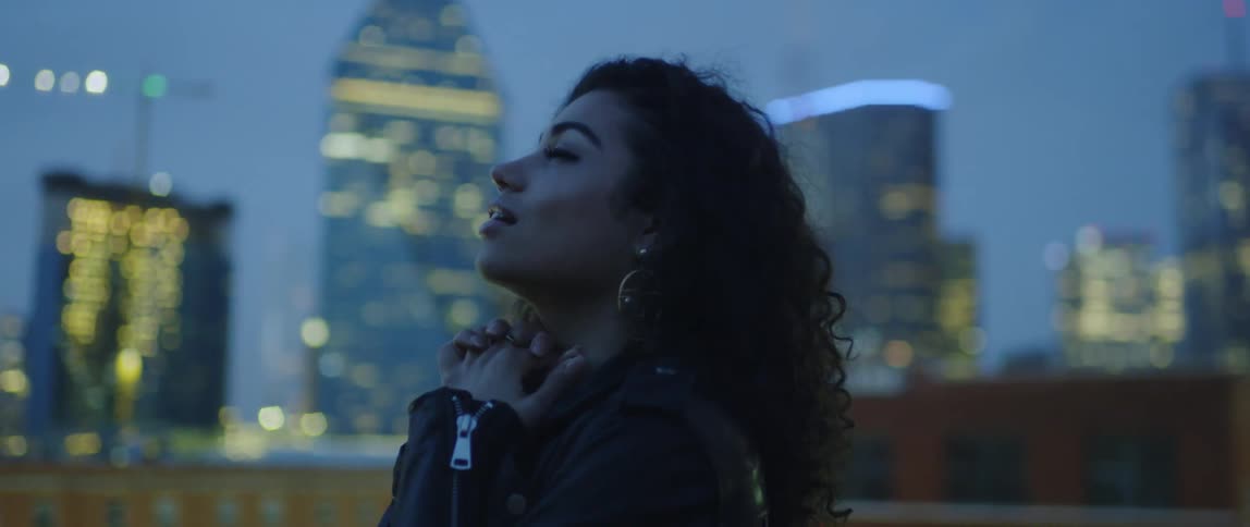 A woman looks around while on a rooftop