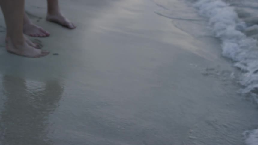 The tide flows onto two peoples feet