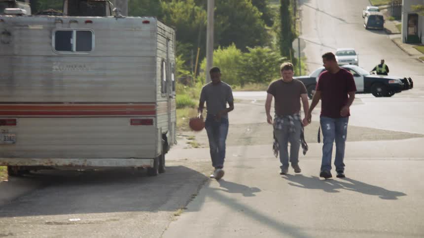 Three men walk on the street with a basketball