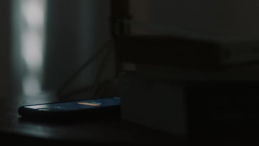 The phone flashes on in the dark room