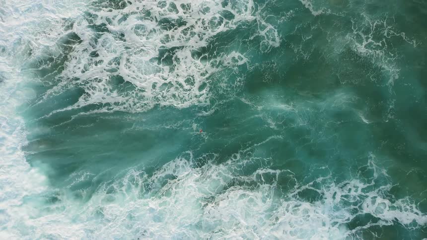 A person in red floats on the ocean waters