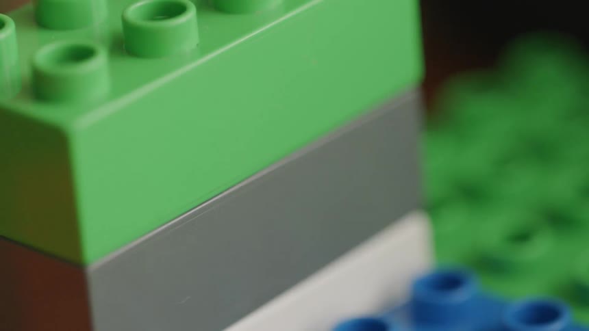 A boy is playing with lego bricks inside in daylight