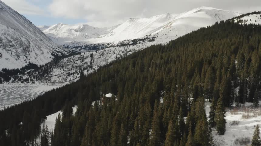 The mountain range is covered with snow before the forest