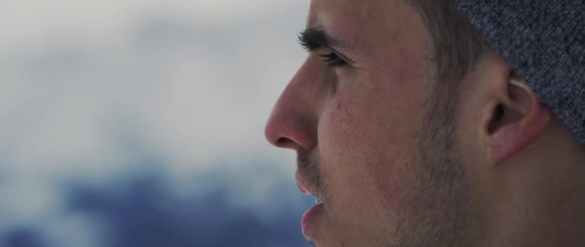 A man is standing outside on a winter day staring into the distance