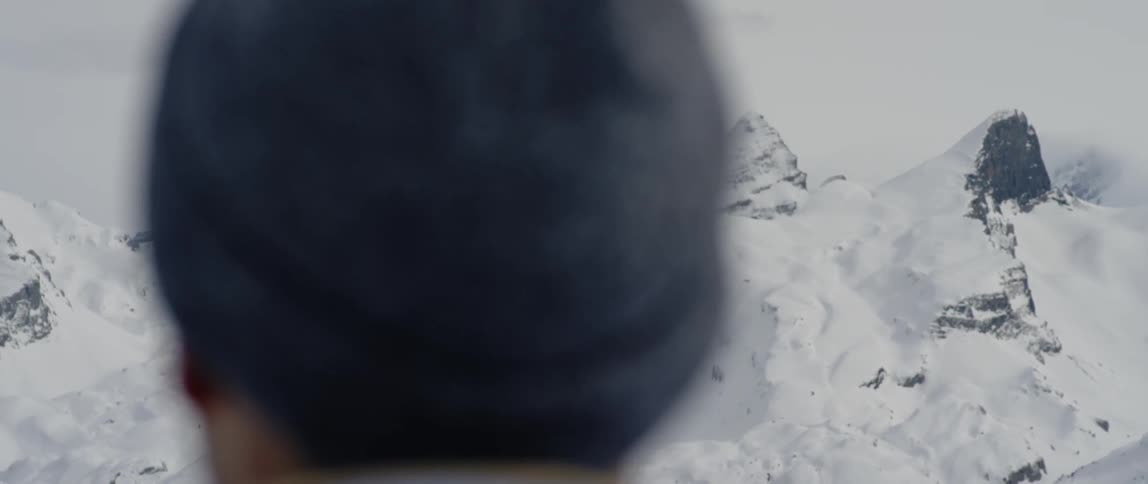 A man looks out onto the snow covered mountains