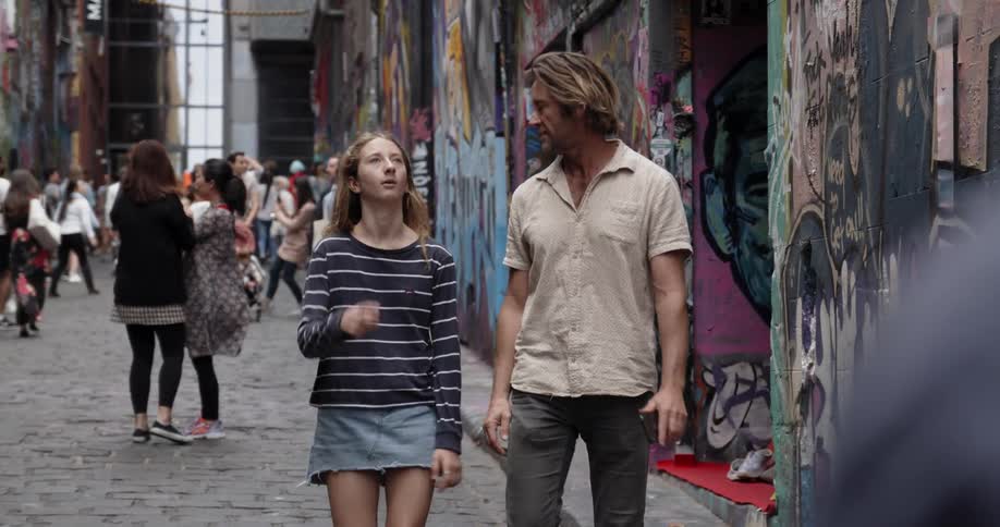 A man and young girl observe graffiti