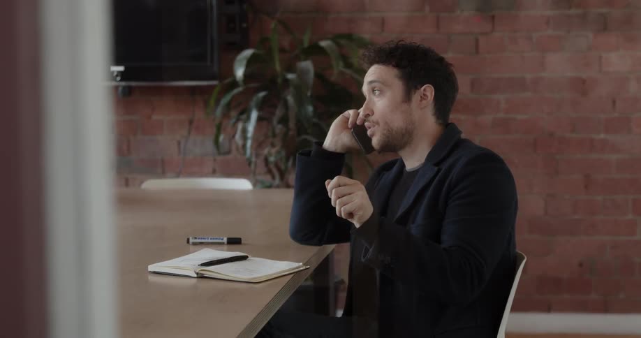 Man sitting at a large conference table and talking on his phone