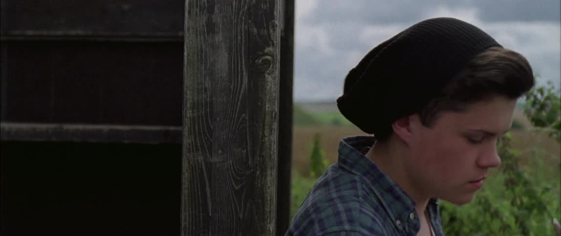 A man peeks around the wooden corner