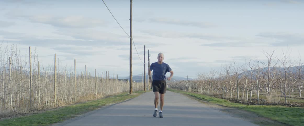 A man is slowly jogging down the road