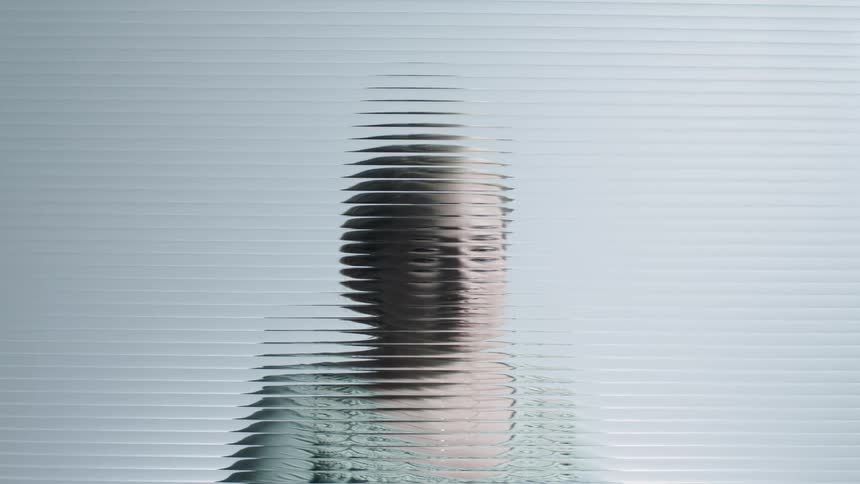 Woman sits behind textured glass