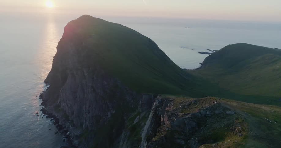 The sun sets over a coastal mountain