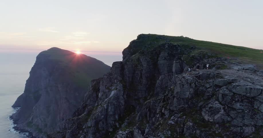 People stand on the edge of a cliff overlooking the ocean