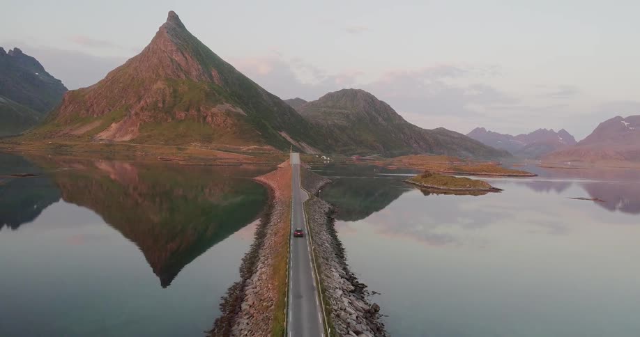 The car travels over the bridge towards the mountain
