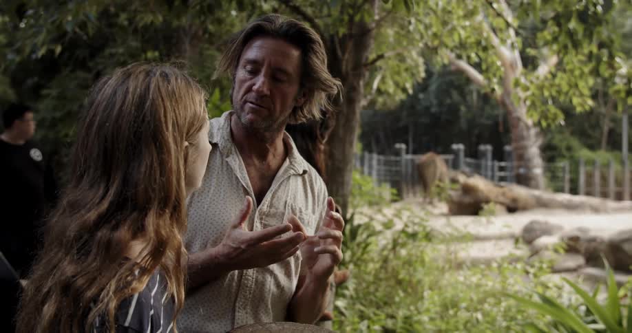 A man and teenager look at animals at a zoo