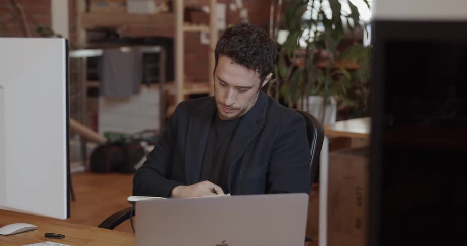 A man is writing in his notebook in the office